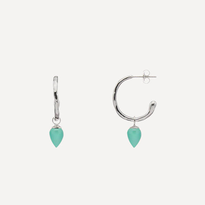 A pair of silver-toned drop earrings, one in a huggie hoop style and one in a curved open hoop style, both featuring a dangling teardrop-shaped mint green stone, shown on a light gray background.