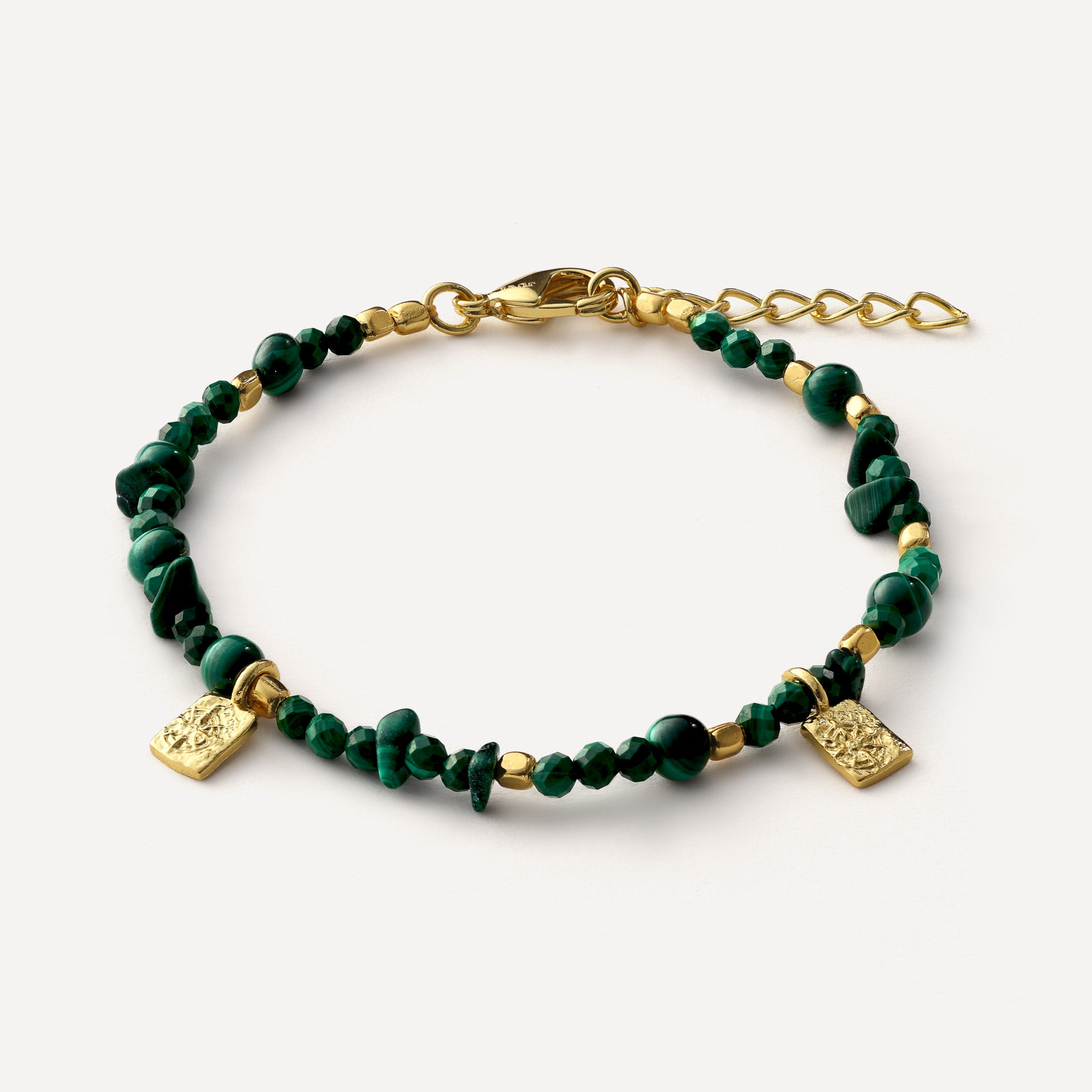 A beaded bracelet featuring dark green malachite beads and polished gold-tone metal accents, including a lobster clasp, extension chain, and two small square charms, shown on a light off-white background.