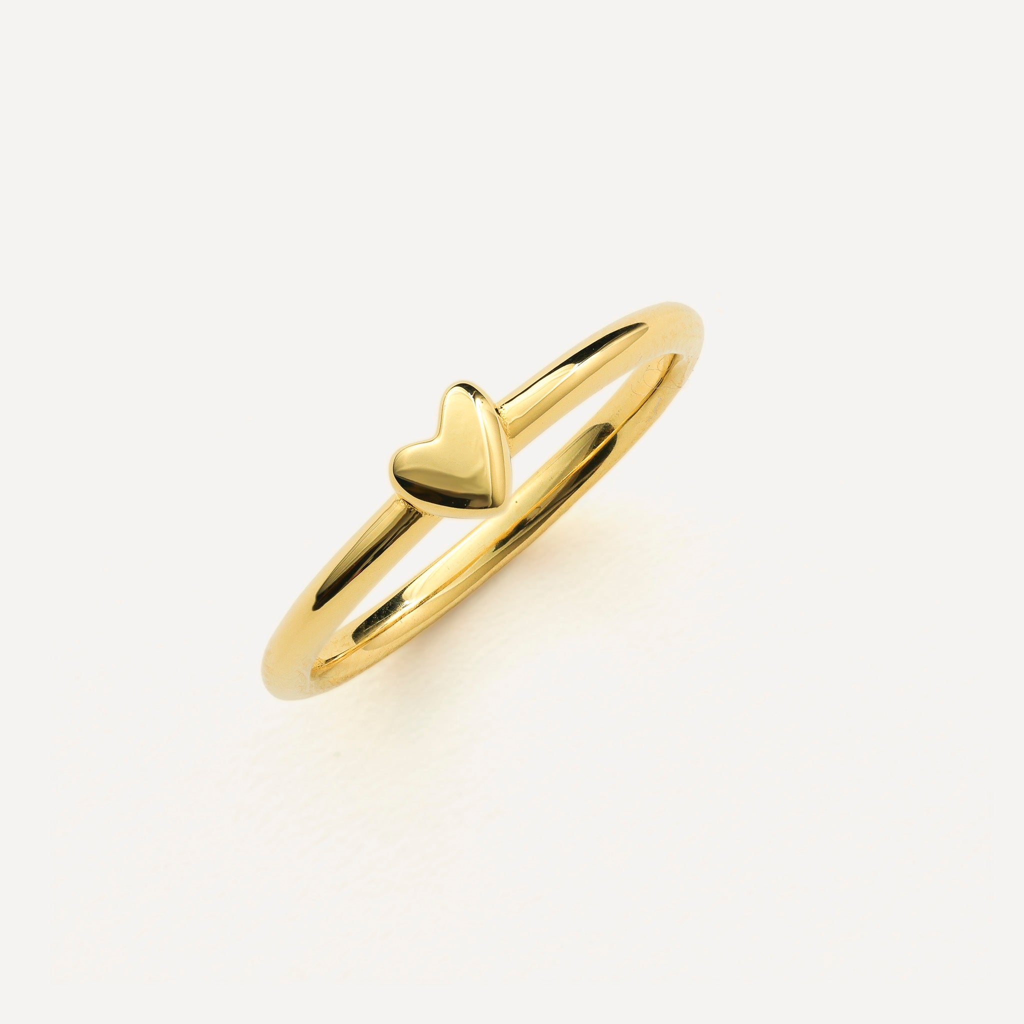 Gold ring with a heart design on a light background